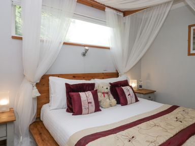 A bedroom with a bed with white and burgundy pillows and a teddy bear at Lake Lodge in Bowness-On-Windermere