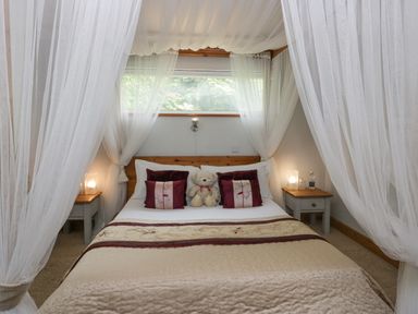 A bedroom with a bed with a teddy bear and pillows and bedside tables with lamps at Lake Lodge in Bowness-On-Windermere