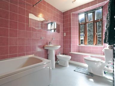 A bathroom with a bathtub sink bidet toilet and window at Honeysuckle Cottage in Bowness