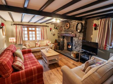 A living room with sofas a stone fireplace and a television at Gunpowder Cottage Langdale