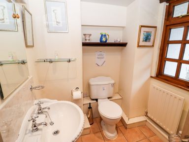 A bathroom with a white sink and toilet a wooden window and a radiator at Gunpowder Cottage in Langdale