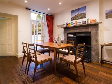 A dining room with a wooden table and six chairs and a fireplace with books on the mantel at Orrest Range in Windermere
