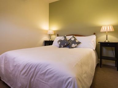 A bedroom with a double bed two pillows on the bed two bedside tables with lamps at Orrest Range in Windermere