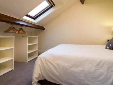 A bedroom with a bed white shelves and a skylight at Orrest Range in Windermere