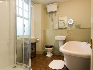 A bathroom with a shower, toilet, pedestal sink, clawfoot bathtub, and window at Orrest Range in Windermere
