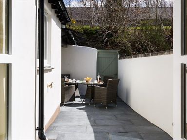 A patio with a table and four wicker chairs set for drinks and snacks at Orrest Range in Windermere