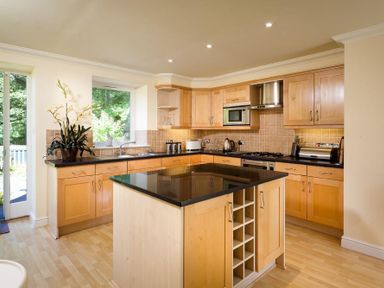 A kitchen with wooden cabinets a black countertop and a kitchen island at The Old Barn in Ambleside