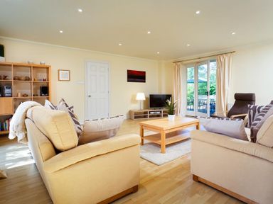 A living room with sofas a coffee table a TV and shelving at The Old Barn in Ambleside
