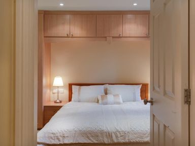A bedroom with a bed lamp and overhead cabinets at The Old Barn in Ambleside