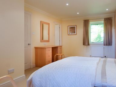 A bedroom with a bed desk mirror chair window and curtains at The Old Barn in Ambleside