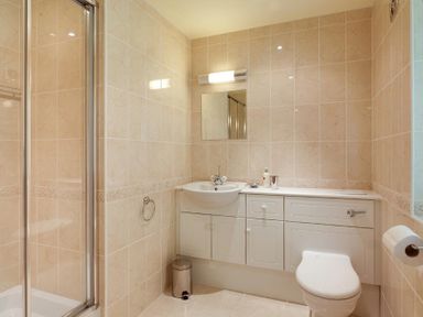 A bathroom with a shower enclosure sink with cabinet toilet and mirror at The Old Barn in Ambleside