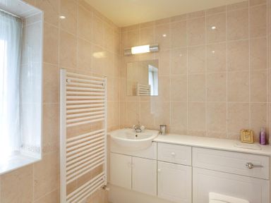 A bathroom with a sink mirror and towel radiator at The Old Barn in Ambleside