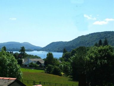 A landscape with a lake surrounded by hills and trees with houses and fields in the foreground at The Old Barn in Ambleside