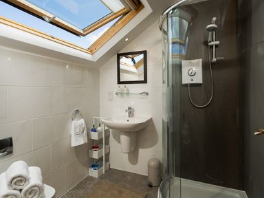 A bathroom with a skylight window sink mirror shower and towel rack at Bowderstone in Keswick