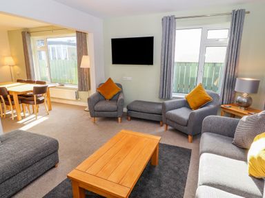 A living room with gray armchairs and a wooden coffee table next to a dining area at Bowderstone in Keswick