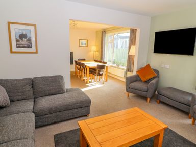 A living room with gray sofa armchair and wooden coffee table connected to dining area at Bowderstone in Keswick