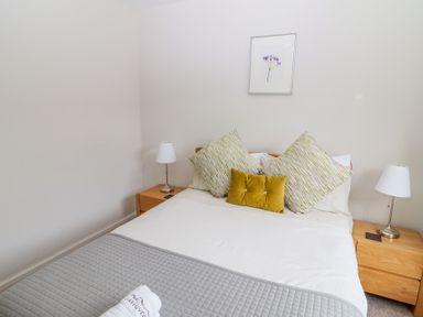 A bedroom with a bed two bedside tables with lamps and a framed flower picture on the wall at Bowderstone in Keswick