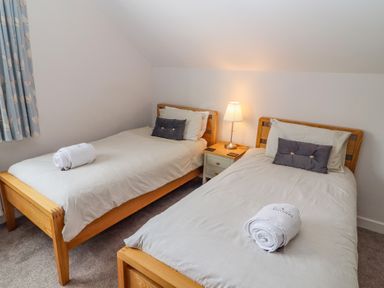 A bedroom with two single beds a bedside table and a lamp at Bowderstone in Keswick