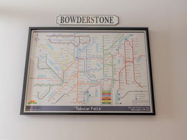 A framed map titled Tubular Fells showing a network of routes with a Bowderstone sign above it at Bowderstone in Keswick