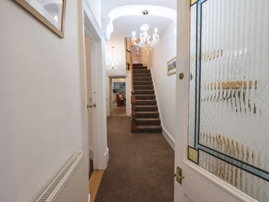 A hallway with carpeted stairs and chandeliers at Number Twenty in Keswick