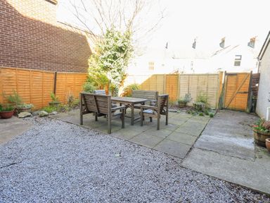 An outdoor patio area with wooden table and chairs surrounded by plants and wooden fencing at Number Twenty in Keswick