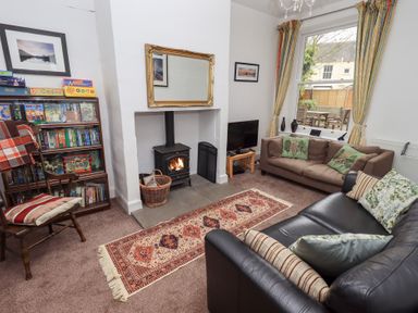 A living room with a wood stove fireplace a bookshelf a television and two sofas at Number Twenty in Keswick