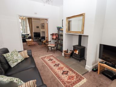 A sitting room with a fireplace a rug and a sofa with cushions at Number Twenty in Keswick