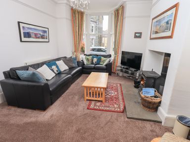 A living room with black sofas a wooden coffee table a TV and a fireplace at Number Twenty in Keswick