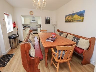 A dining area with wooden benches and chairs around a wooden table next to a kitchen at Number Twenty in Keswick
