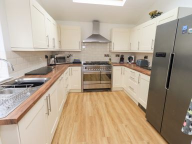 A kitchen with white cabinets wooden countertops a stainless steel fridge oven and a sink at Number Twenty in Keswick