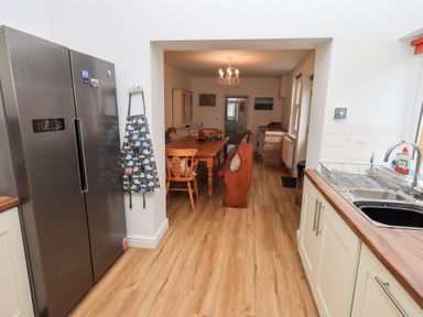 A kitchen with a stainless steel refrigerator a sink with countertop and a dining area with a wooden table and chairs at Number Twenty in Keswick
