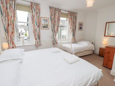 A bedroom with two beds floral curtains and wooden furniture at Number Twenty in Keswick