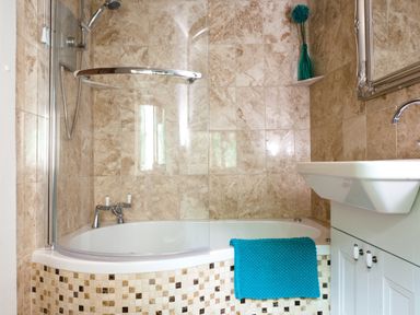 A bathroom with a bathtub shower combination and a white sink cabinet at Burrow Cottage in Bowness
