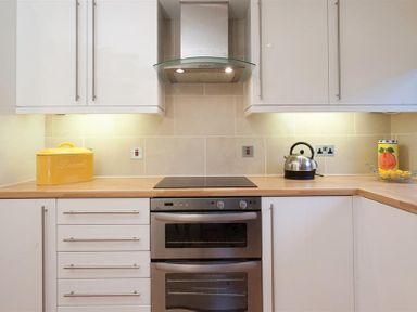 A kitchen countertop with a yellow bread box a kettle and a fruit container at Mount Sol in Ambleside