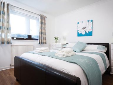 A bedroom with a double bed with folded towels bedside tables and a window with curtains at Mount Sol in Ambleside