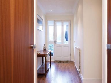 A hallway with a wooden table and white front door at Mount Sol in Ambleside