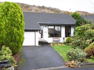 A detached house with a driveway garage and garden surrounded by trees and shrubs at Mount Sol Ambleside