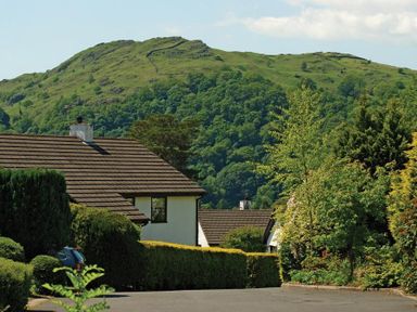 A street with houses and greenery with a hill in the background at Mount Sol in Ambleside