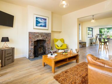 A living room with a brick fireplace a wooden coffee table and modern furniture at Greengarth in Keswick