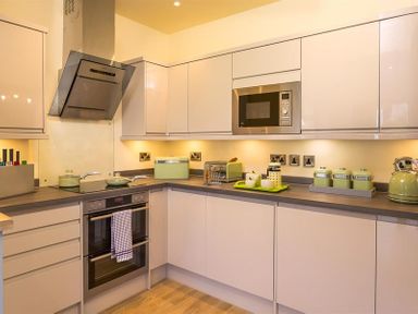 A kitchen with white cabinets a built in microwave an oven stovetop and green kitchen appliances at Greengarth Keswick