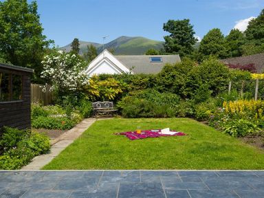 A garden with a lawn blanket and juice a bench and plants at Greengarth in Keswick