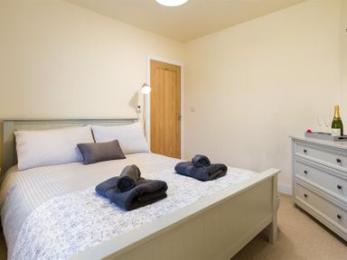 A bedroom with a bed a wooden door and a dresser with a bottle and glasses at Greengarth in Keswick