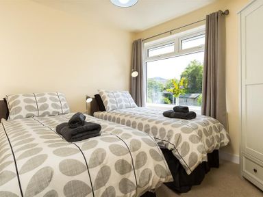 A bedroom with two single beds with patterned bedspreads and folded towels on them at Greengarth in Keswick