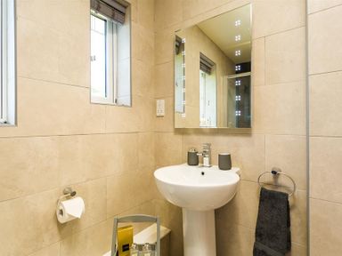 A bathroom with a pedestal sink mirror towel holder and small window at Greengarth in Keswick