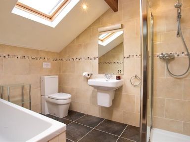 A bathroom with a toilet sink mirror shower and bathtub at Garden Cottage At Coniston in Coniston