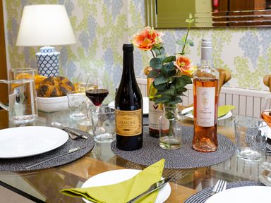 A dining table set with plates glasses cutlery wine bottles and flowers at Pippin Cottage in Keswick