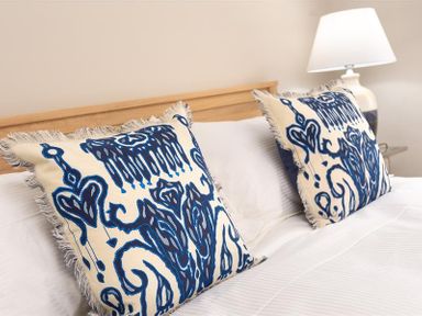 A bed with two patterned pillows and a lamp on a bedside table at Pippin Cottage in Keswick