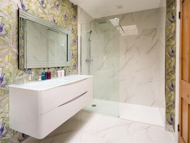 A bathroom with a floating white vanity and a glass shower enclosure at Pippin Cottage in Keswick