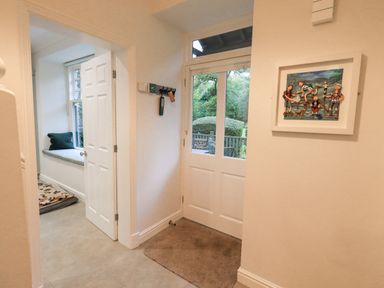 An entryway with a white door and a window seat with a cushion and pillow at Pudding Cottage in Ambleside