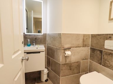 A small bathroom with a sink and mirror on the left and a toilet on the right at Pudding Cottage in Ambleside